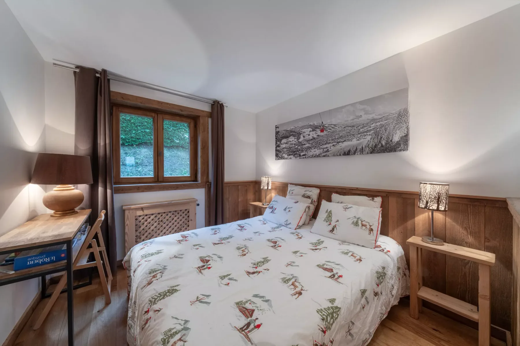 A bedroom with a floral bedspread and a wood-framed window.