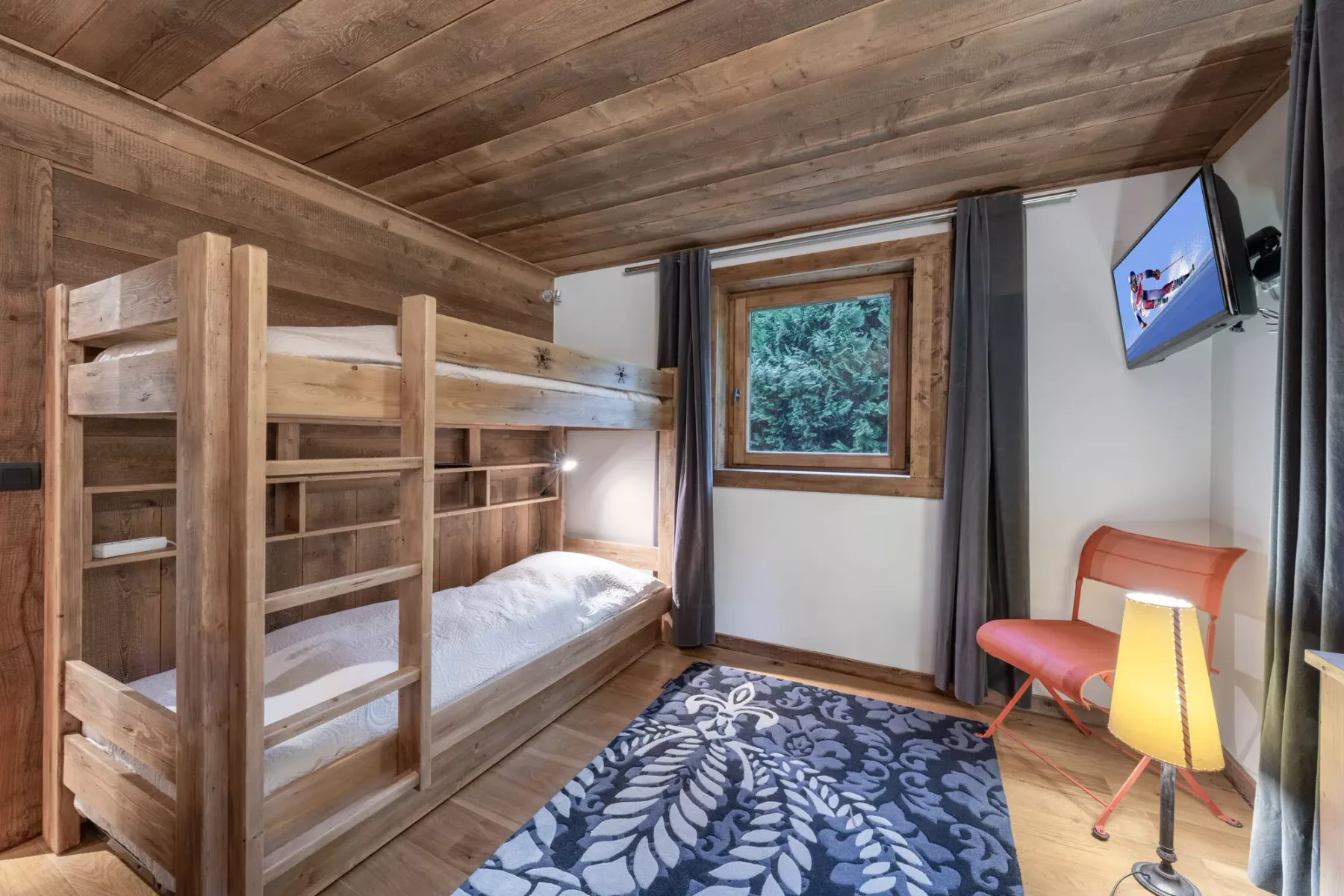 Un dormitorio con literas de madera, una ventana y una alfombra estampada.