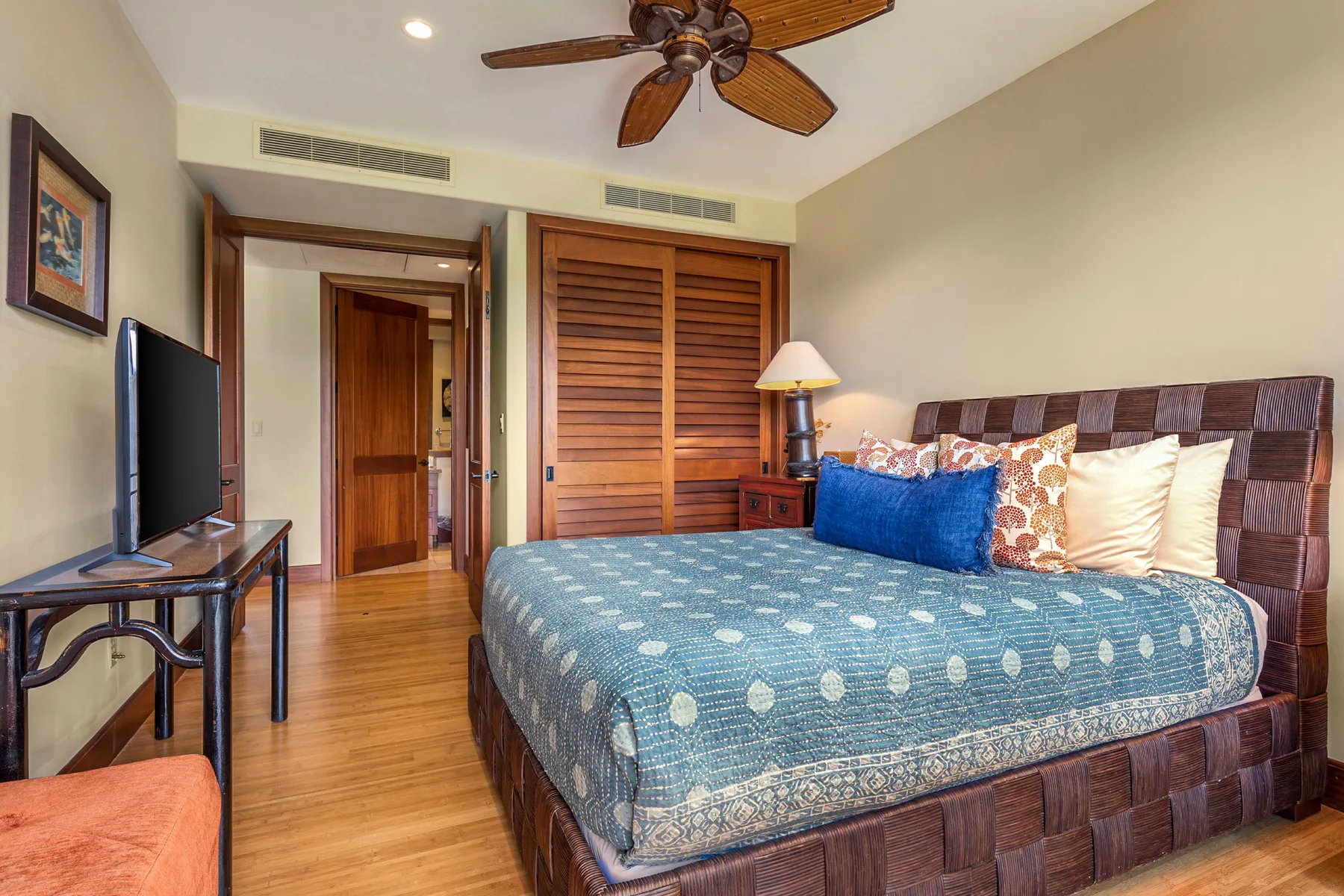 A bedroom with a patterned bed and wooden closet doors.