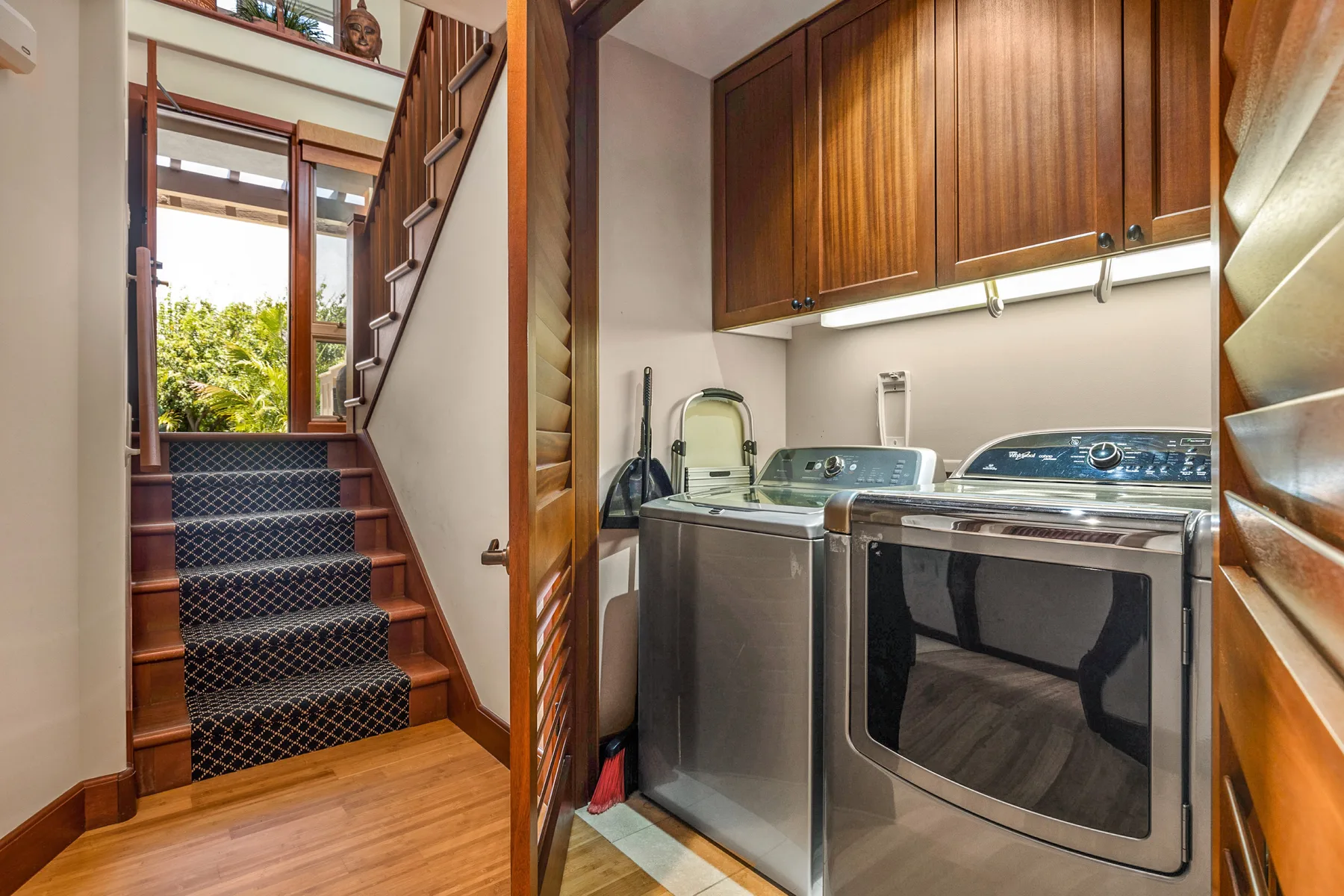 A laundry area with a washer and dryer beneath wooden cabinets.