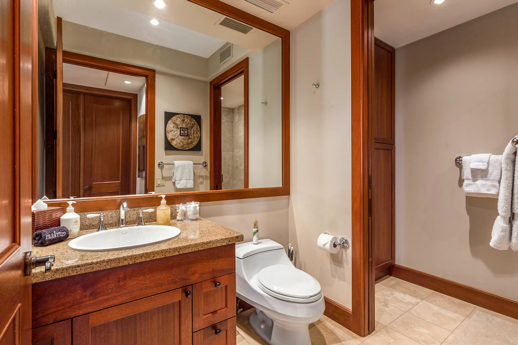 A bathroom vanity and toilet sit beside a large wall mirror.