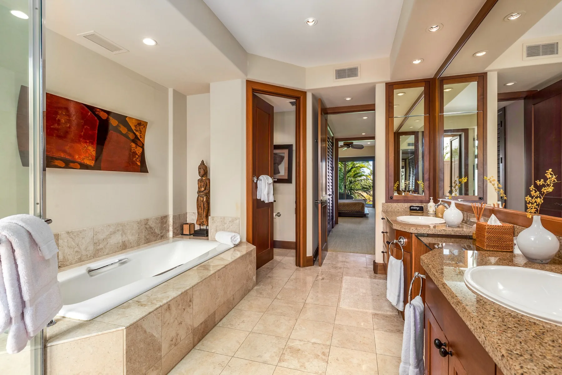 A spacious bathroom with a bathtub, double sinks, and mirrored cabinets.