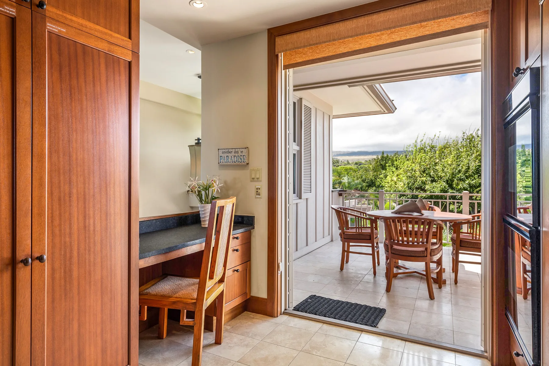 A dining area opens onto a tiled terrace with a table and chairs.
