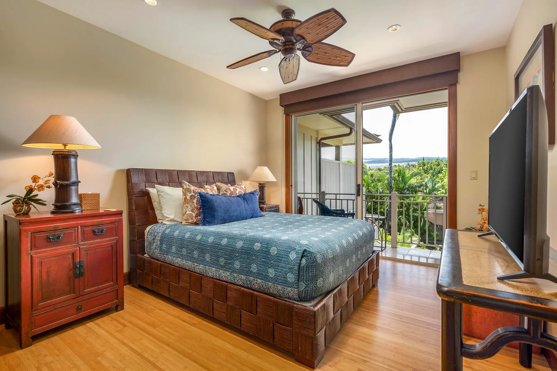 A bedroom with a bed beside sliding glass doors opening onto a balcony.