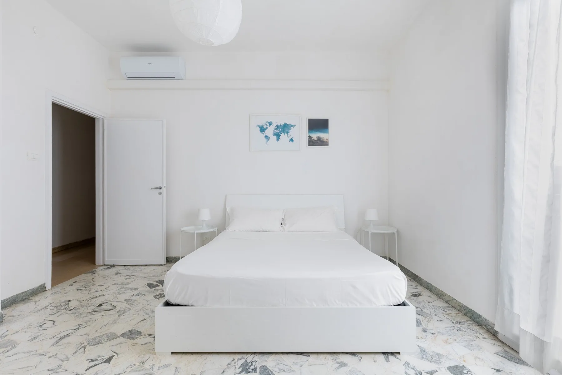Un dormitorio luminoso con una cama bien tendida y cortinas claras.