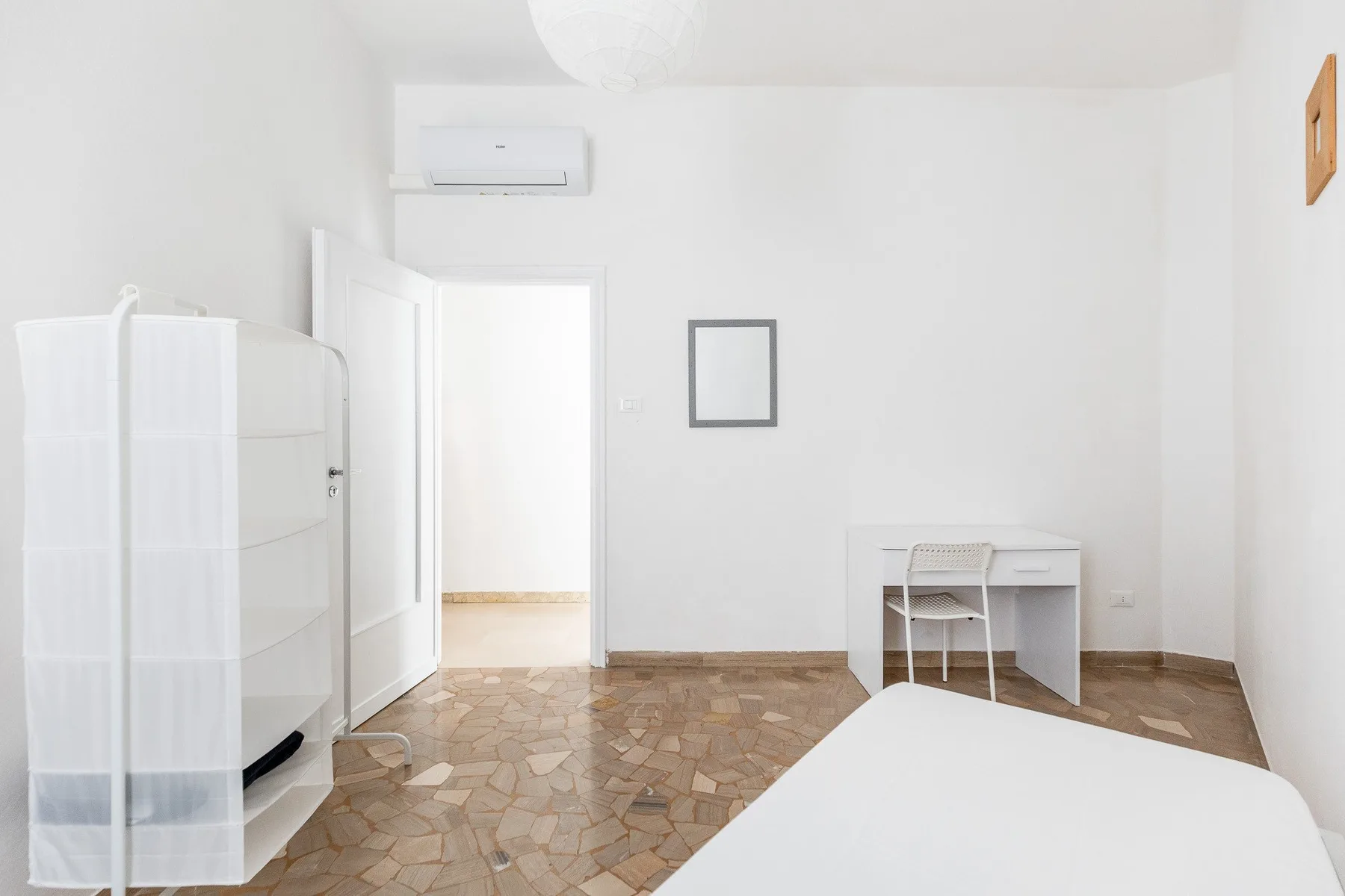 Un dormitorio luminoso con una cama, un escritorio y una silla.