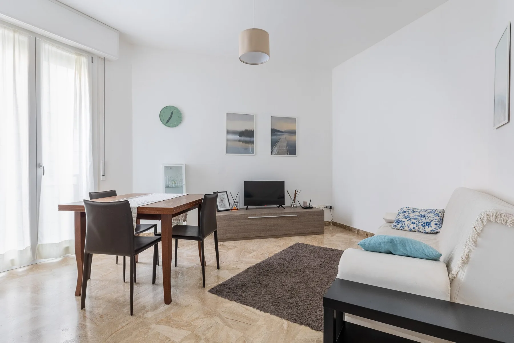 Un salón luminoso con mesa de comedor, televisor y asientos.