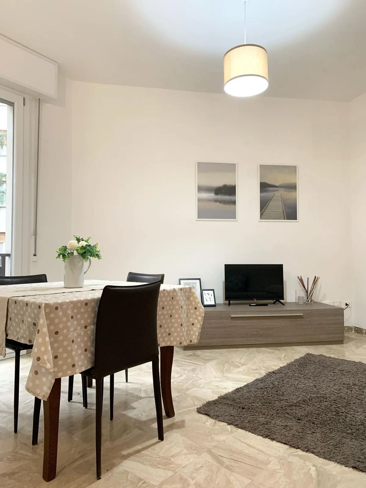 Un comedor y sala de estar con una mesa, asientos y un televisor.