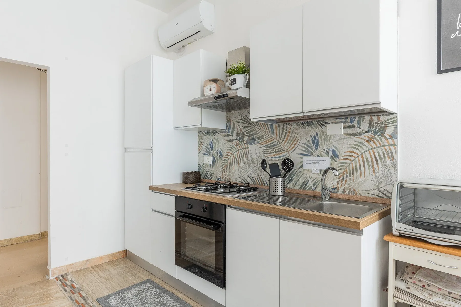 Una cocina luminosa con gabinetes claros, una placa de cocina y un salpicadero estampado.