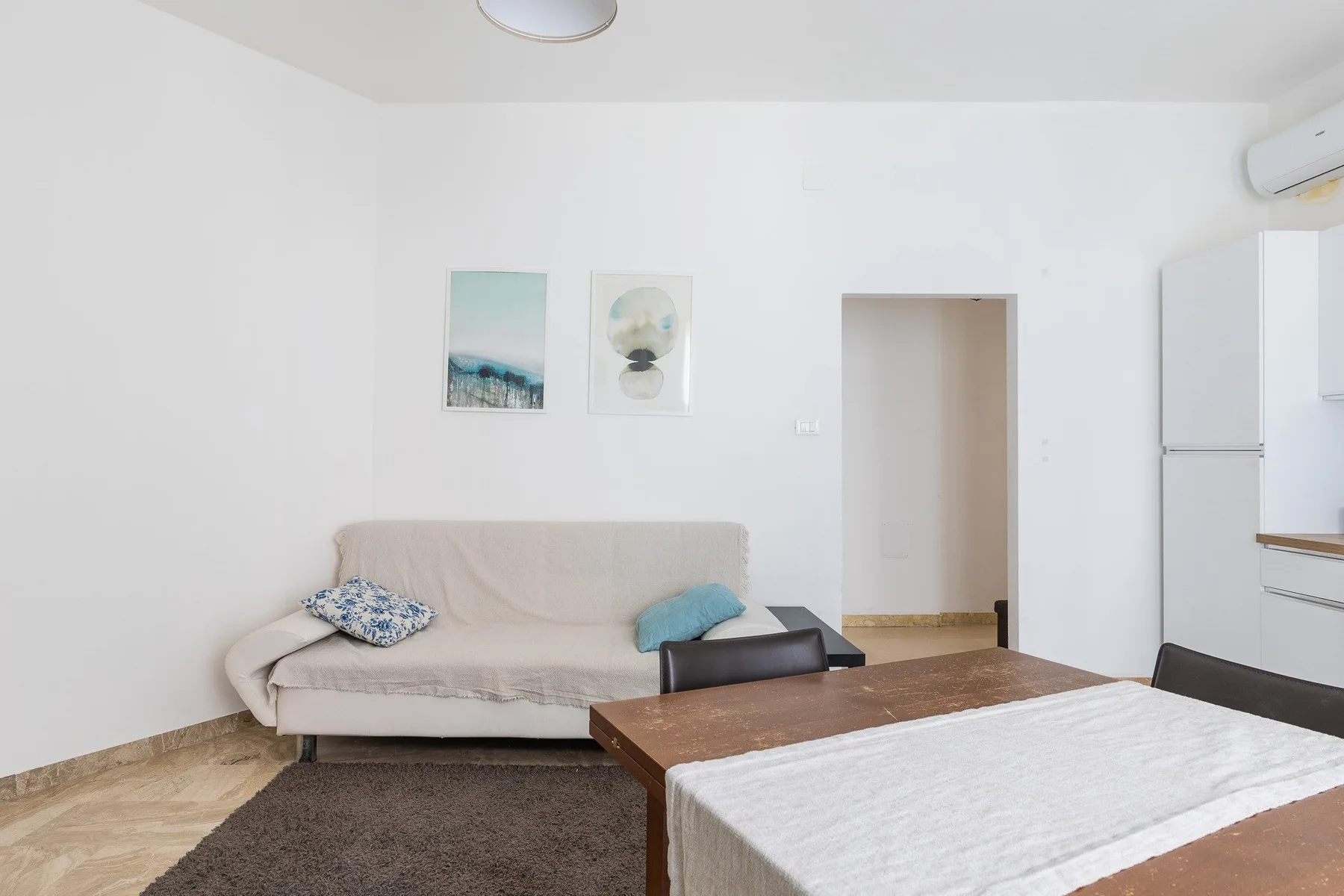 Una sala luminosa con un sofá beige y una mesa de comedor de madera.