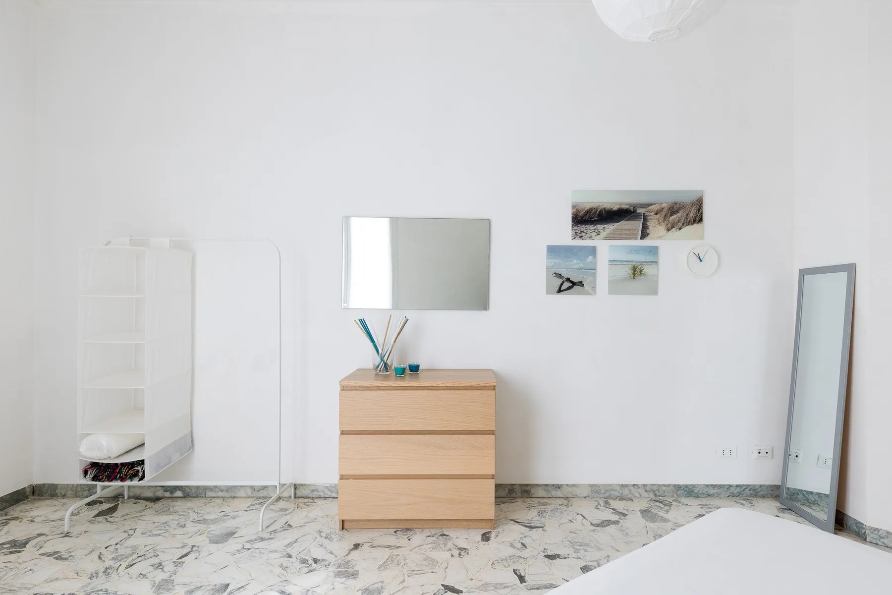 Un dormitorio luminoso con una cómoda de madera, un espejo y cuadros en la pared.