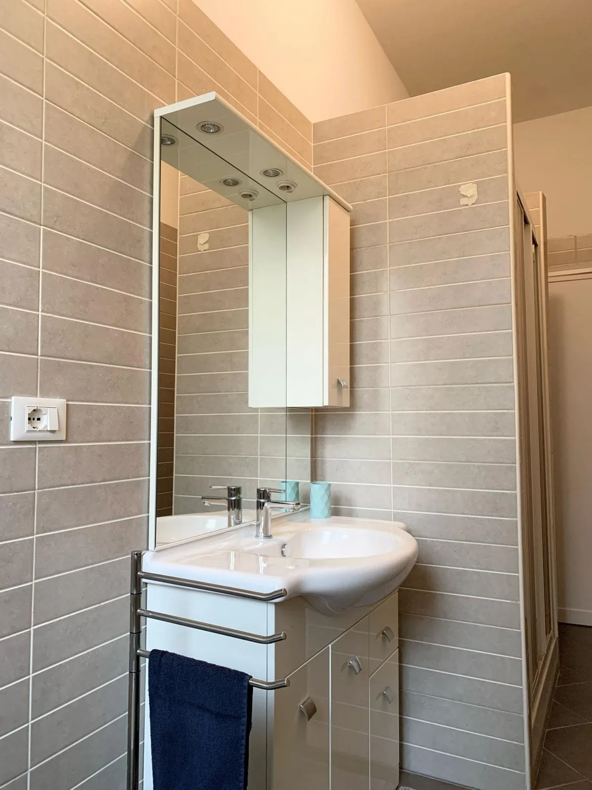 Un baño alicatado con un espejo de pared sobre el lavabo y el mueble.