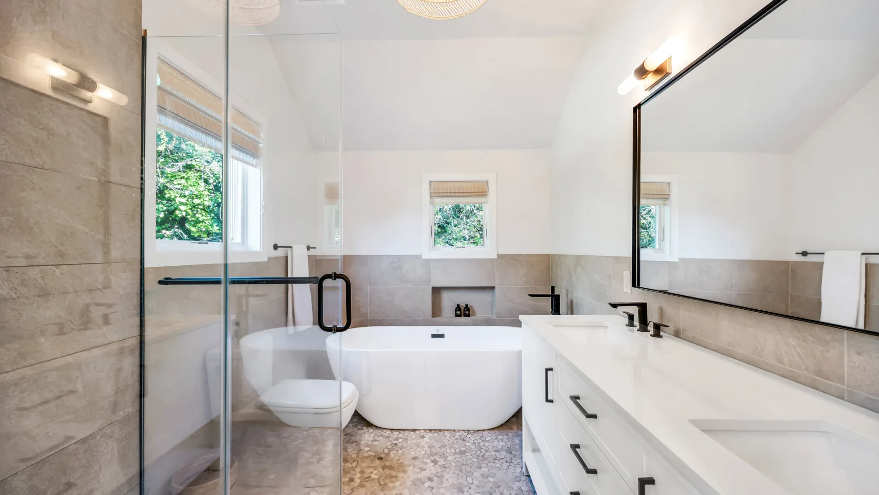 Un baño luminoso con bañera, ducha de vidrio y un largo tocador.