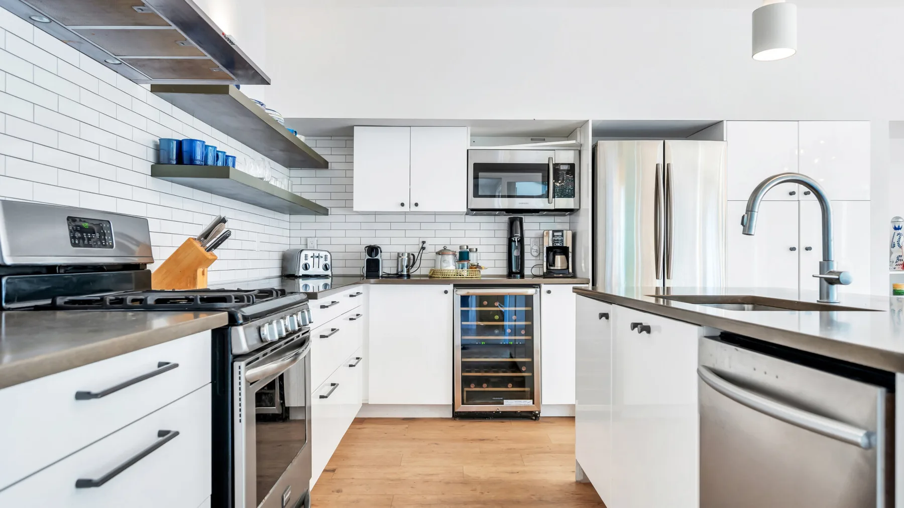 Una cocina moderna con gabinetes blancos, electrodomésticos de acero inoxidable y una isla central.