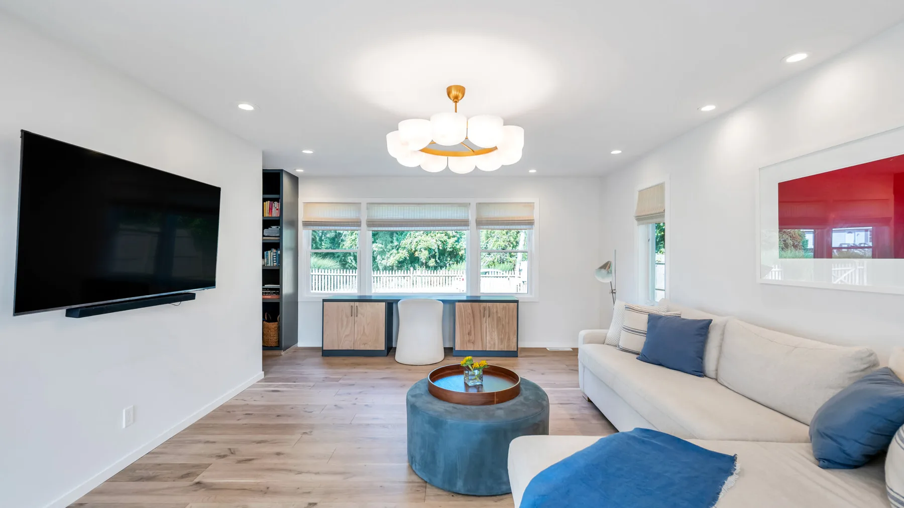 Una sala luminosa con un televisor grande y asientos junto a amplias ventanas.