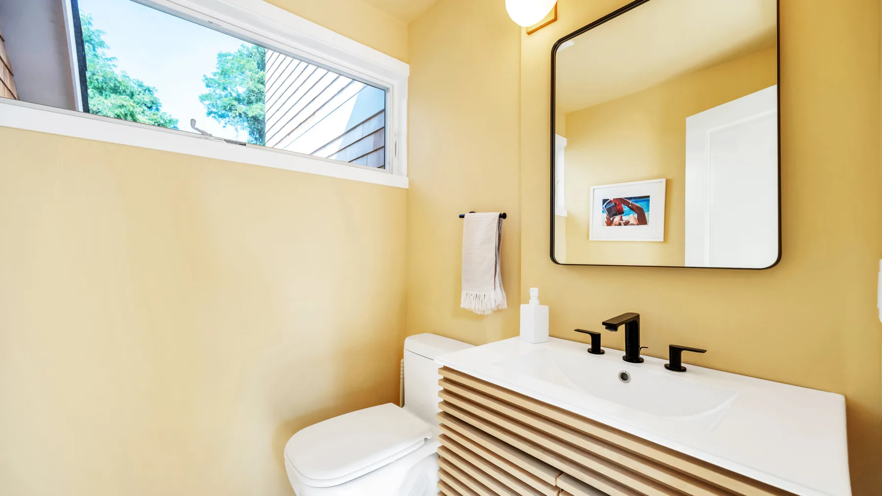 Un baño luminoso con lavabo, espejo e inodoro.