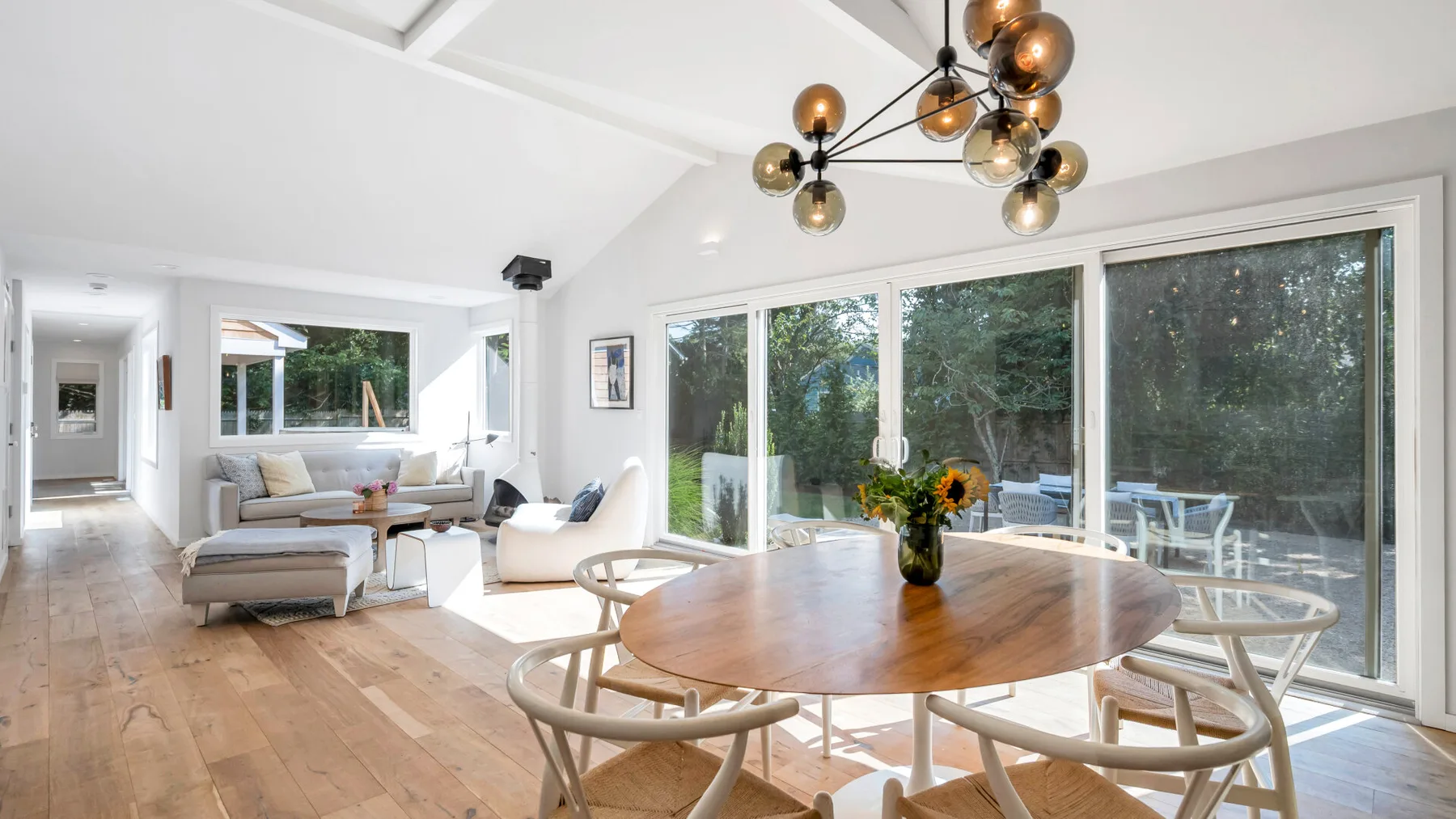 A bright dining area with a wooden table beside large windows.