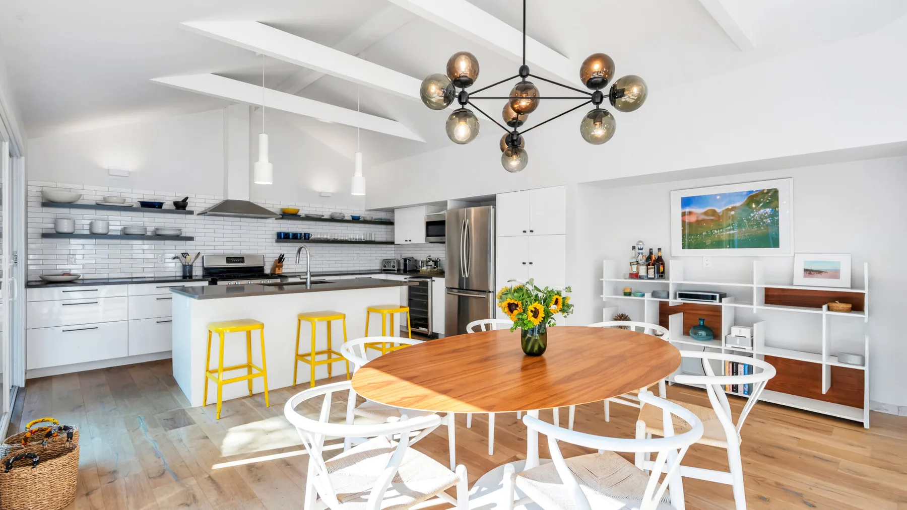 Una luminosa cocina abierta al comedor con una mesa redonda de madera.
