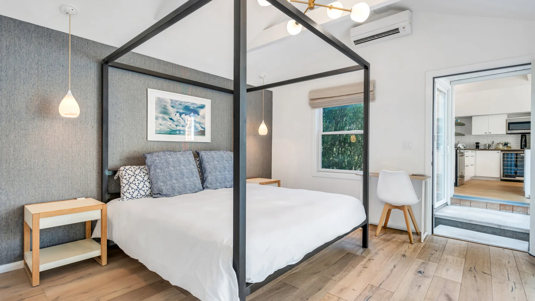 Un dormitorio luminoso con una cama, una mesa auxiliar y una ventana.