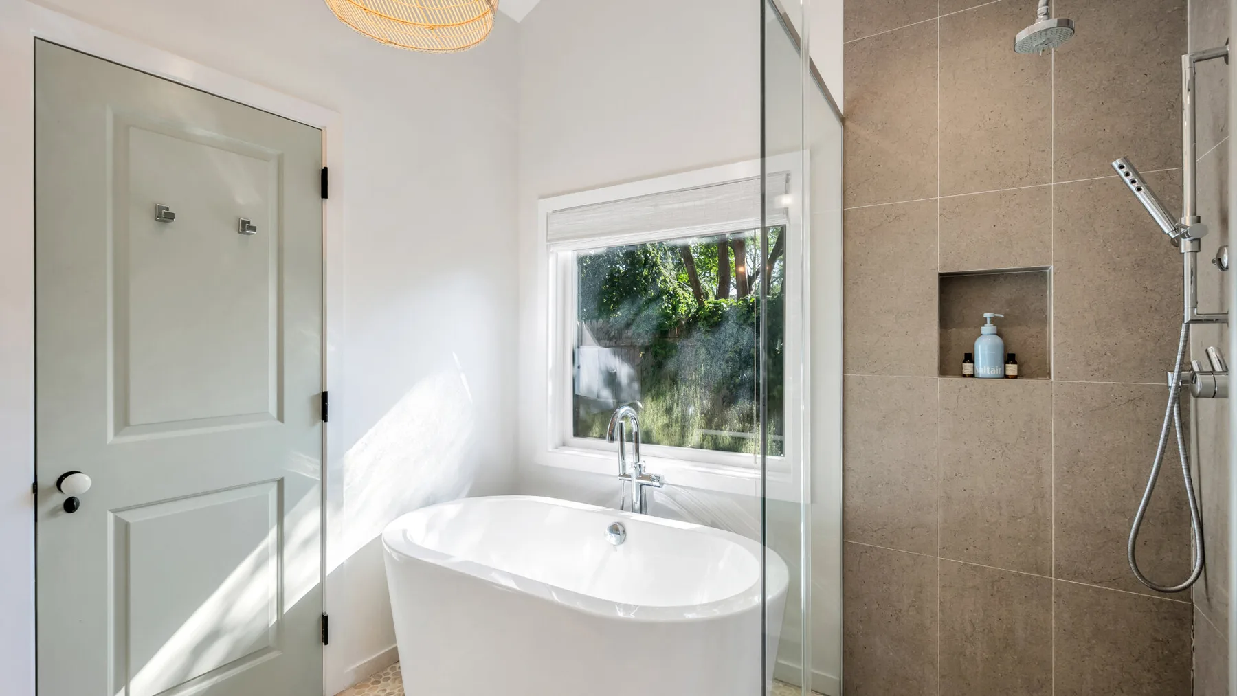 Un baño luminoso con una bañera independiente junto a una ducha de vidrio.
