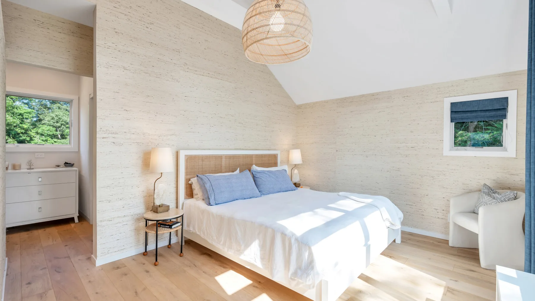 Un dormitorio luminoso con una cama bajo un techo inclinado.