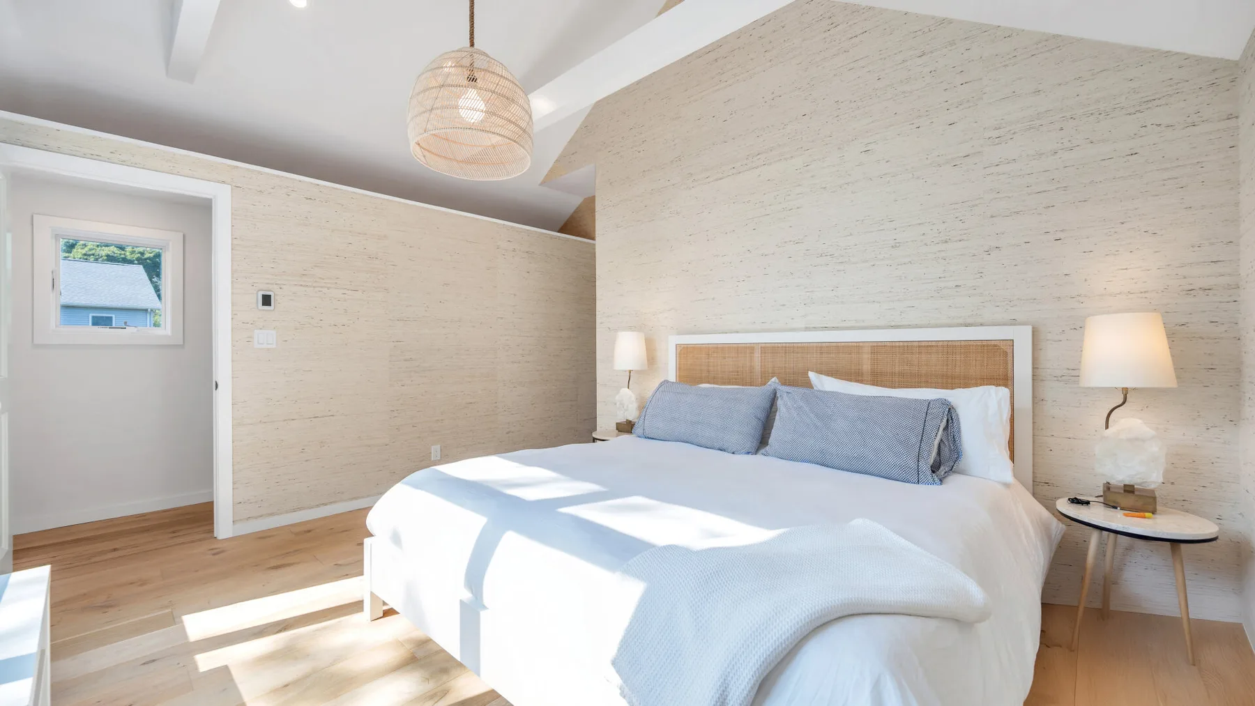 Un dormitorio luminoso con una cama grande y paredes claras con textura.