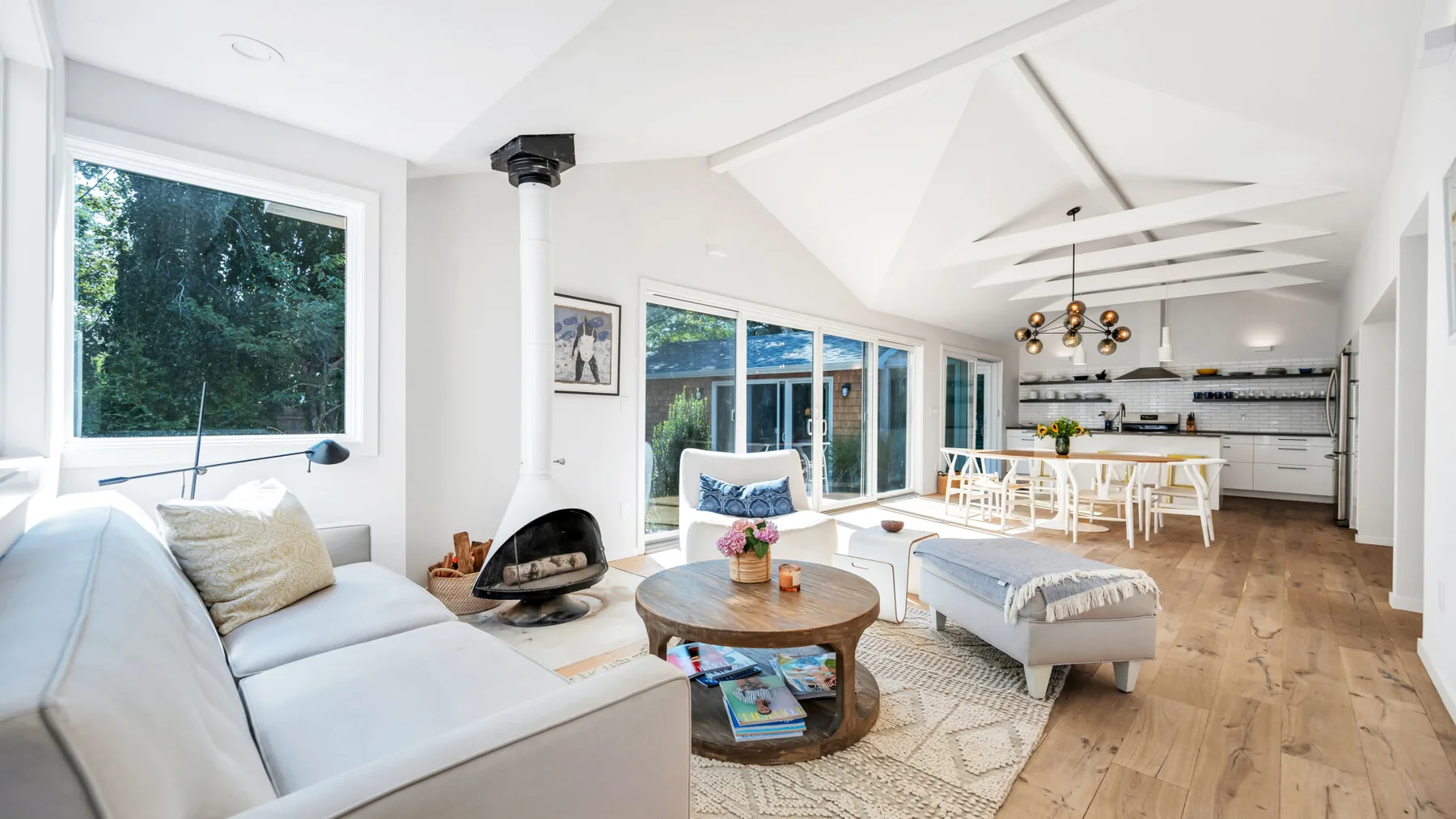 Bright living room with white seating, a fireplace, and large windows.
