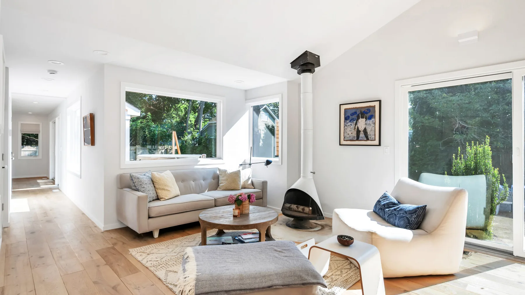 A bright living room with seating around a coffee table and a wood-burning stove.