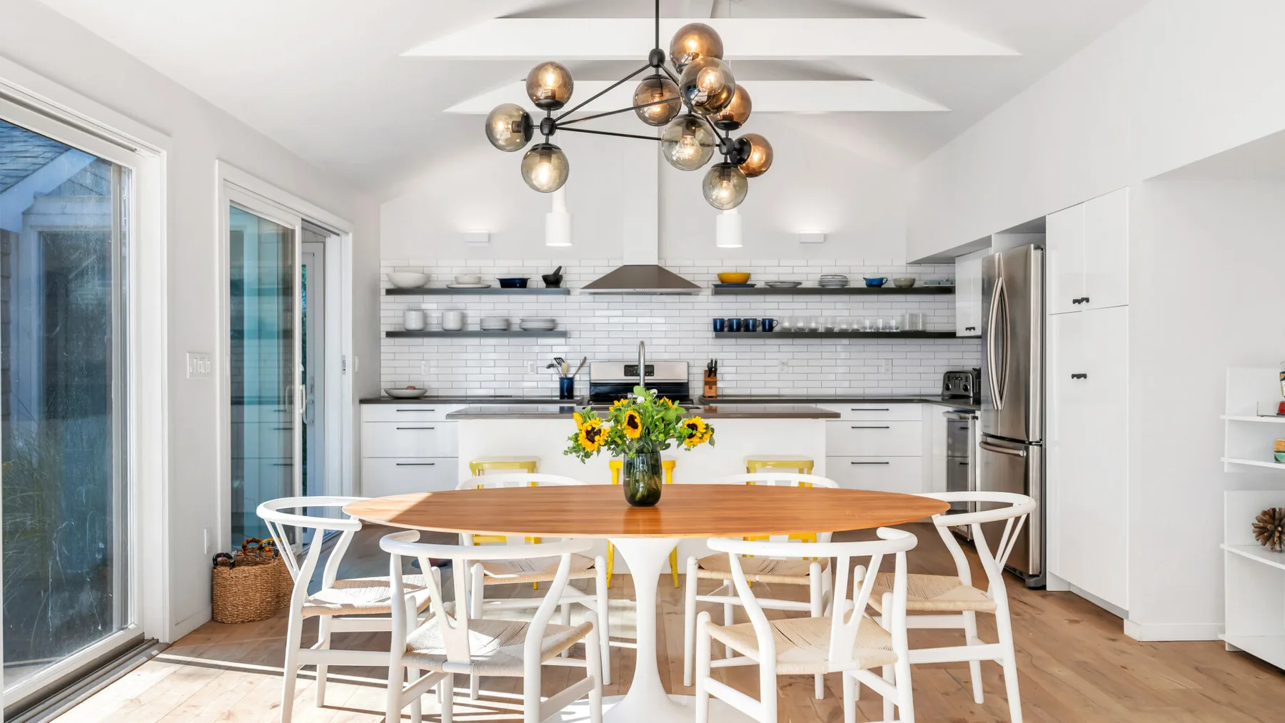 Una luminosa cocina y comedor con una mesa larga y estantes abiertos.