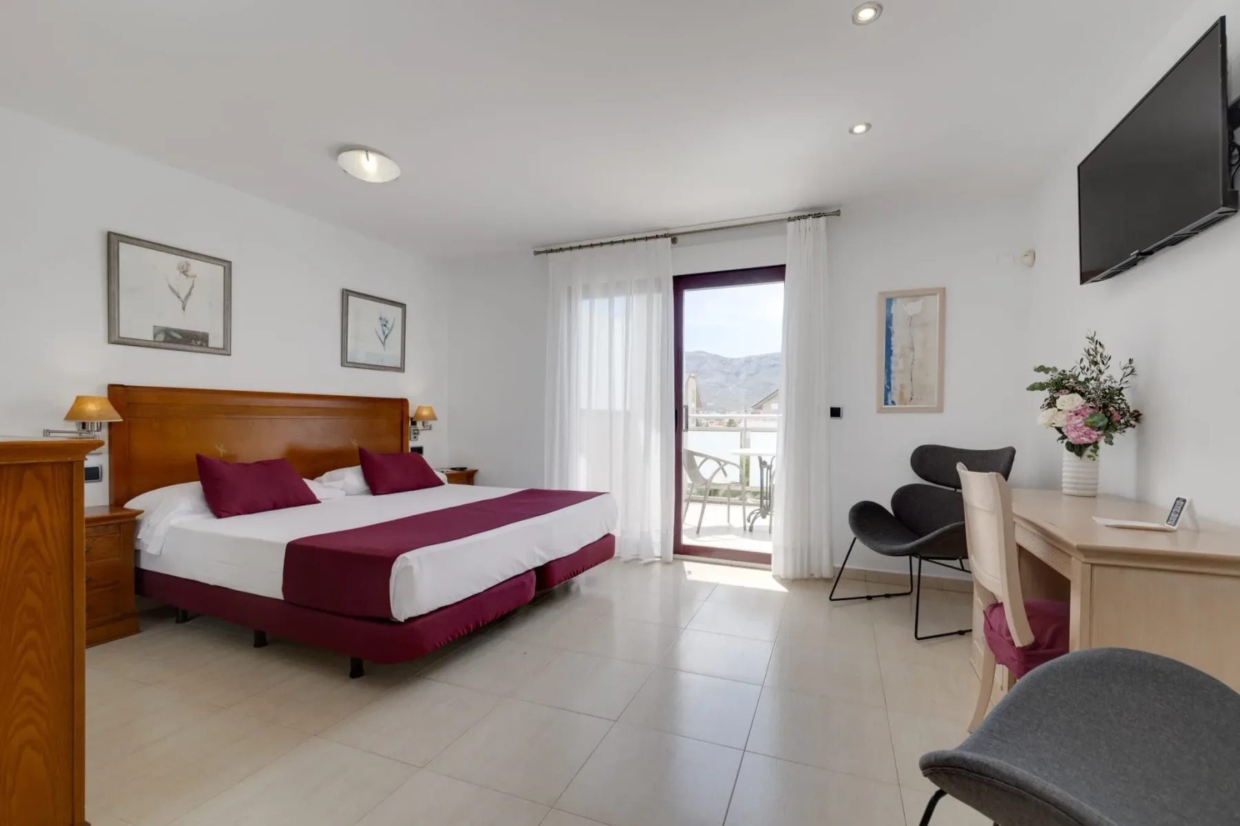 Interior de una habitación doble con una cama y una ventana al balcón.