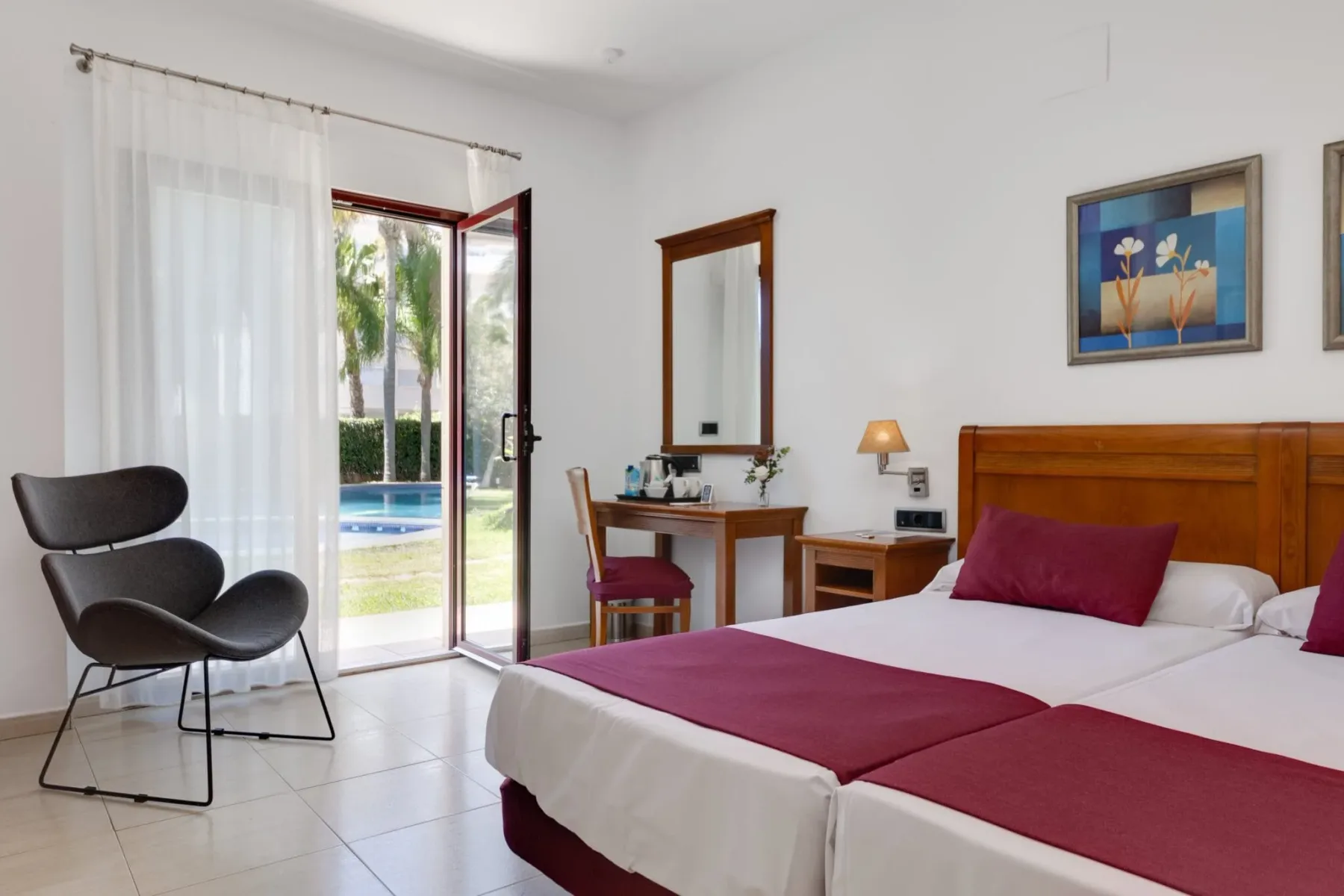 Habitación doble con acceso al jardín, donde se ven camas y una puerta acristalada.