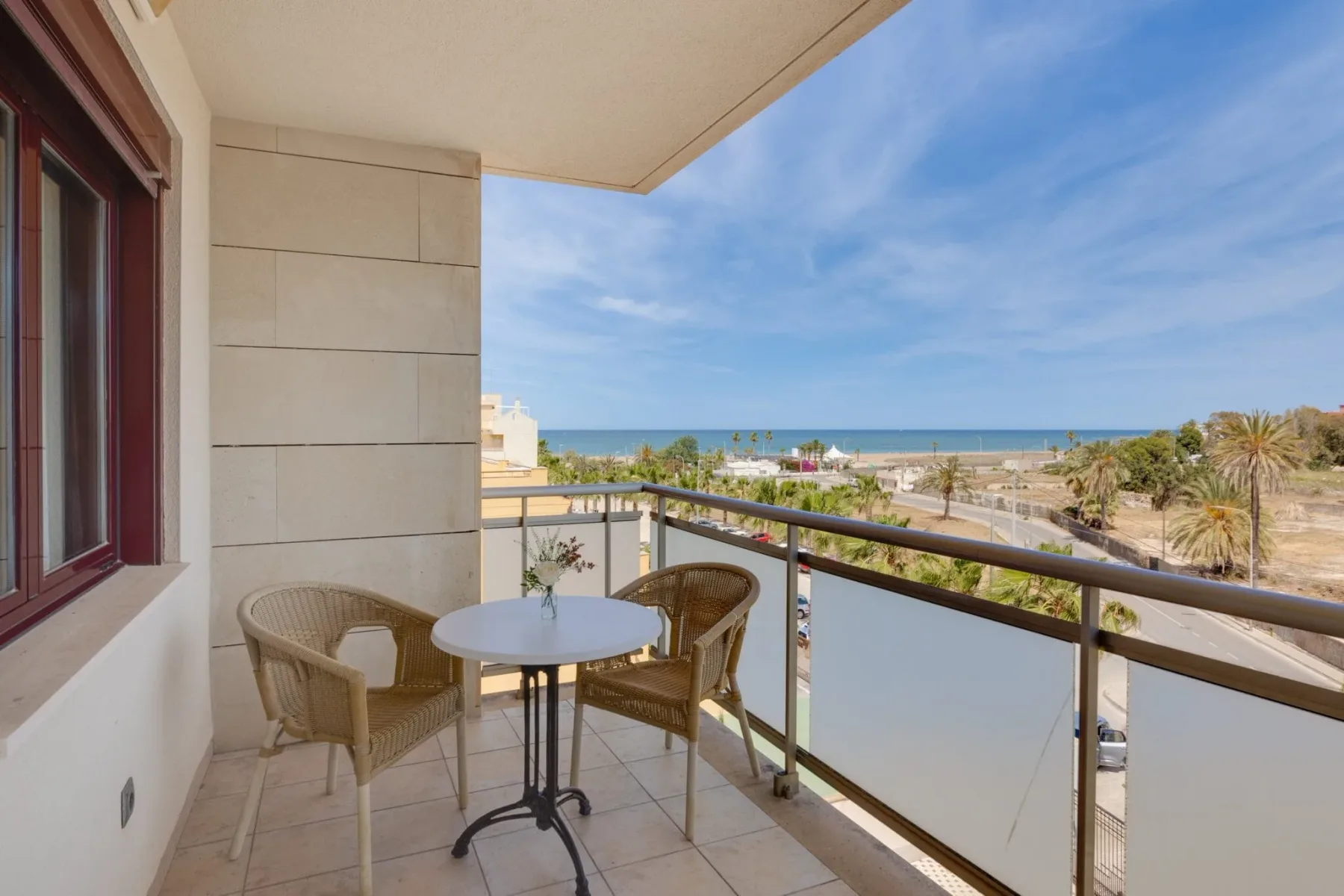 Balcón con mesa de exterior y vistas a la costa.