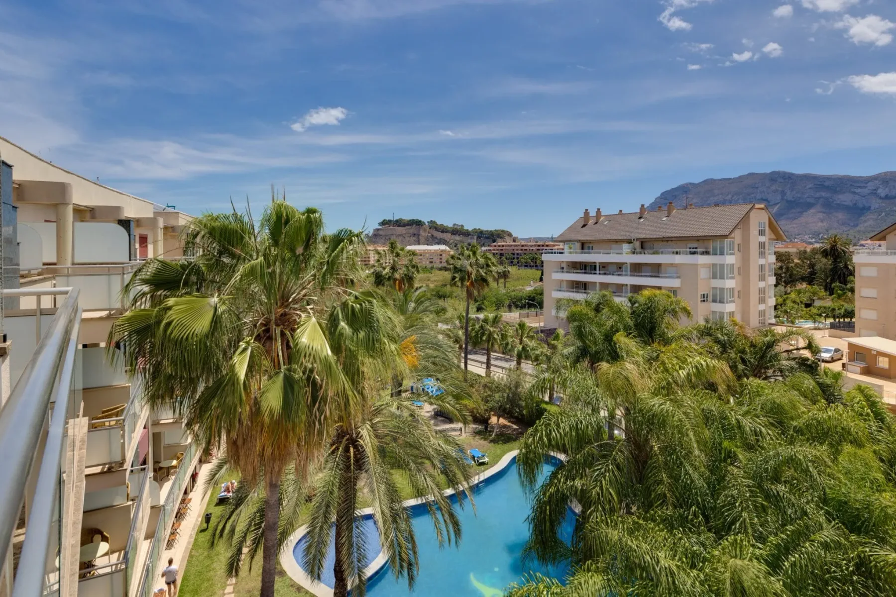 Edificio del hotel, piscina y palmeras vistos desde arriba.
