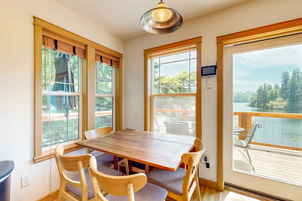 Comedor con una mesa de madera junto a ventanas con vistas al agua.
