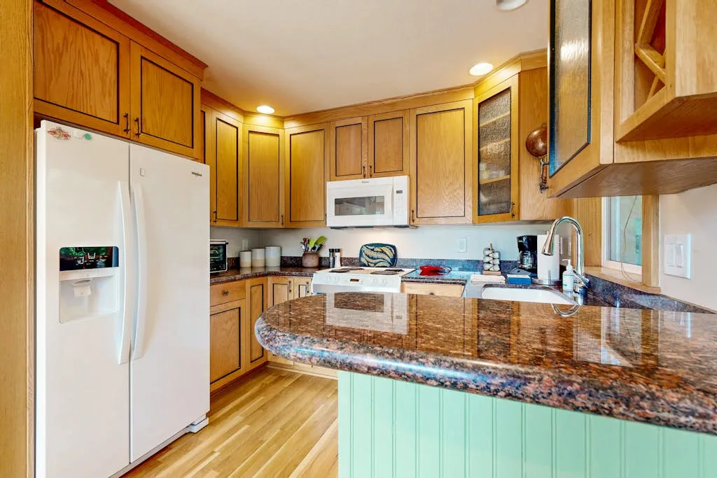 Una cocina con gabinetes de madera, electrodomésticos blancos y una gran isla central.