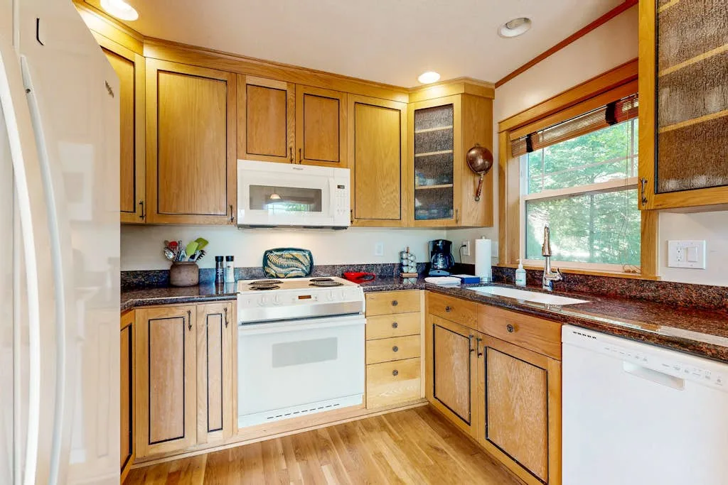 Una cocina luminosa con gabinetes de madera, una estufa y una ventana.