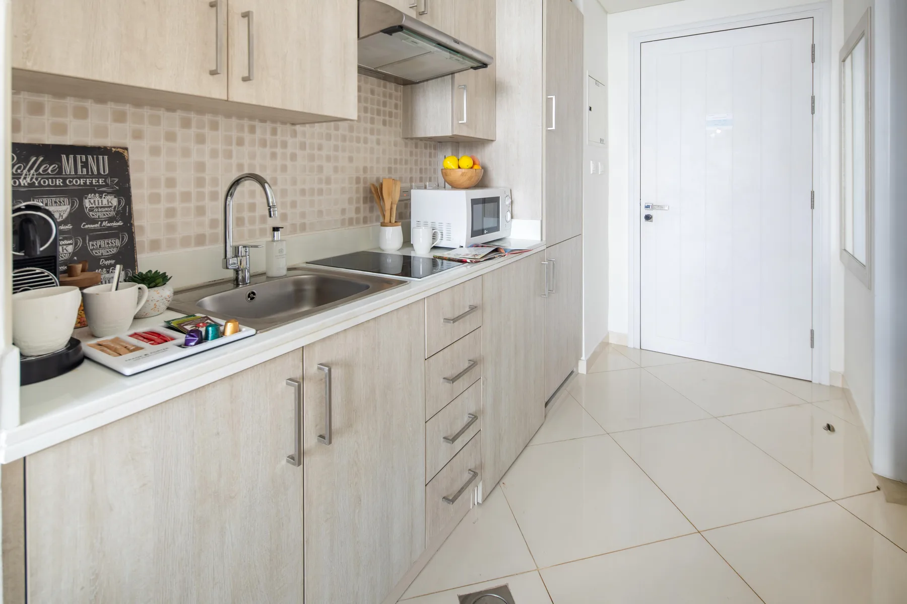 Una cocina compacta con gabinetes claros, una encimera y un fregadero.