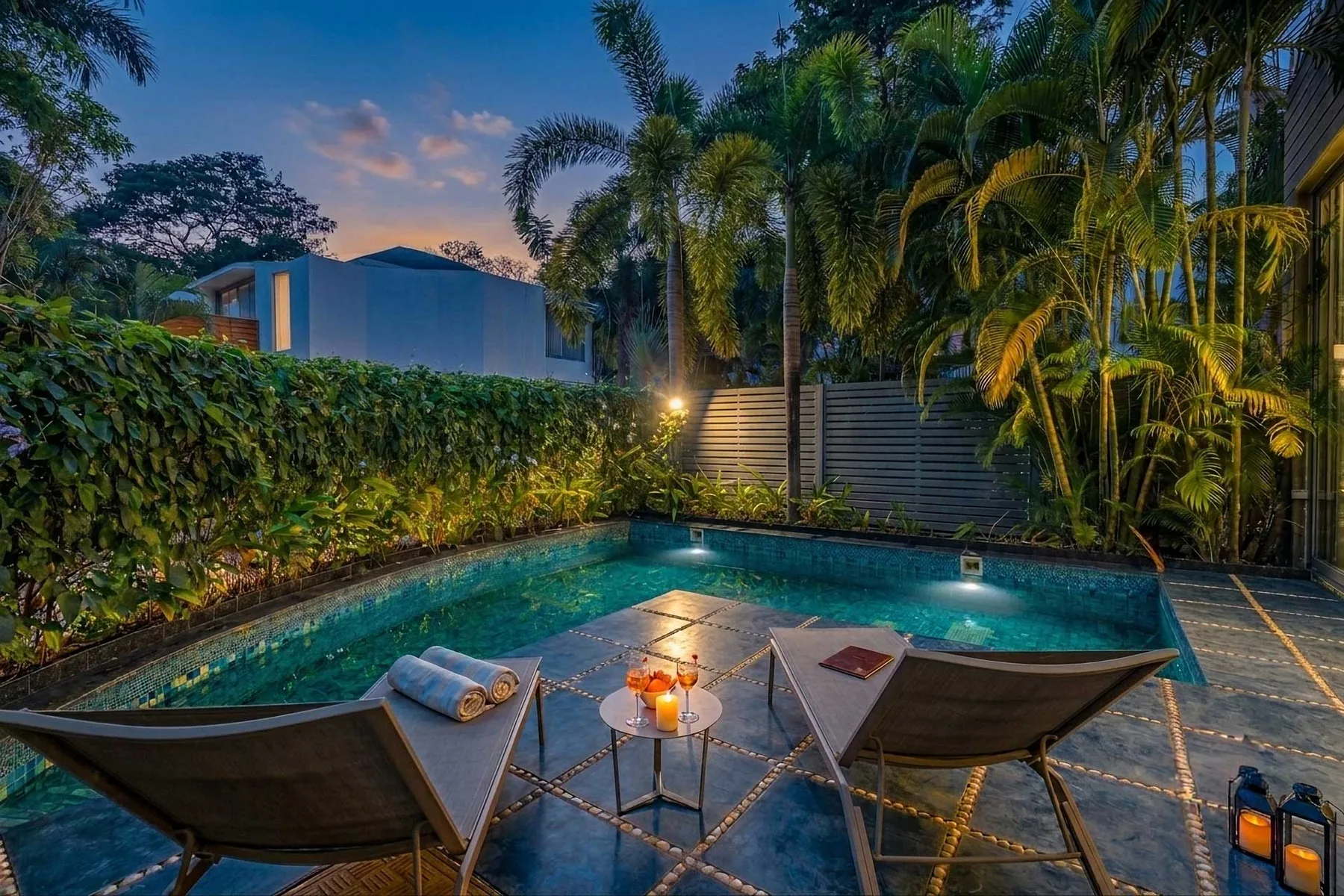 Una piscina al aire libre está rodeada de vegetación tropical, con asientos junto al agua.