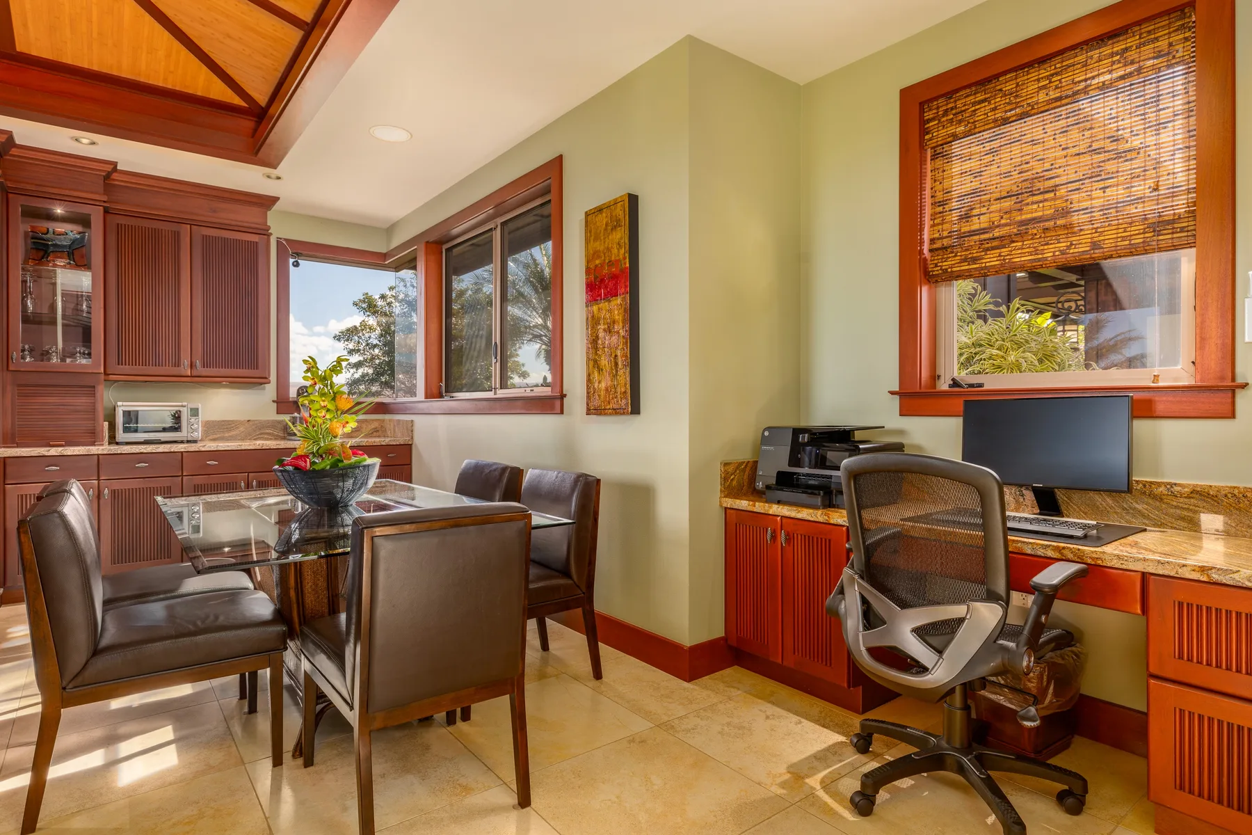 A dining and work area with a table, computer desk, and windows.