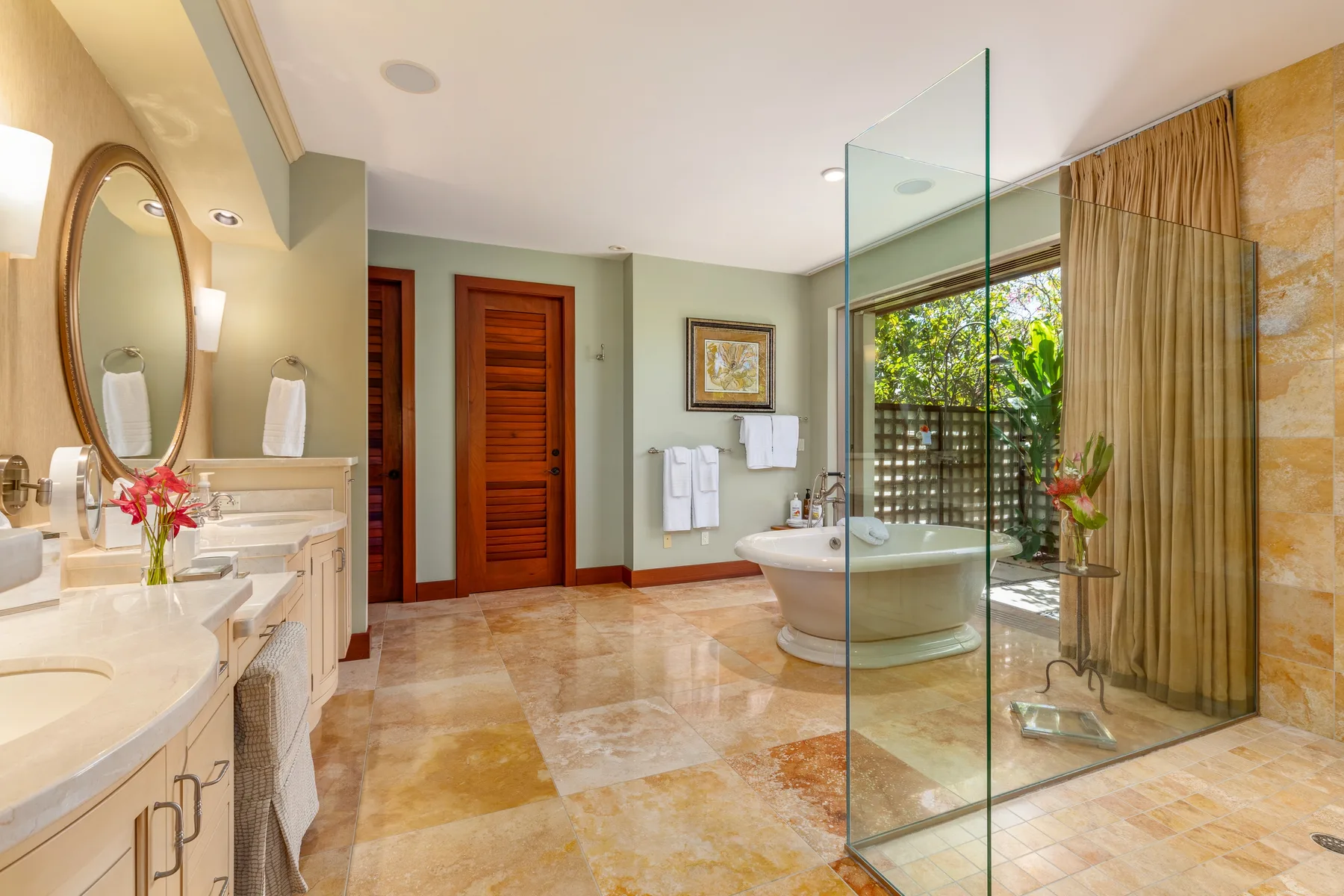 A spacious bathroom with a bathtub, vanity, and glass shower partition.