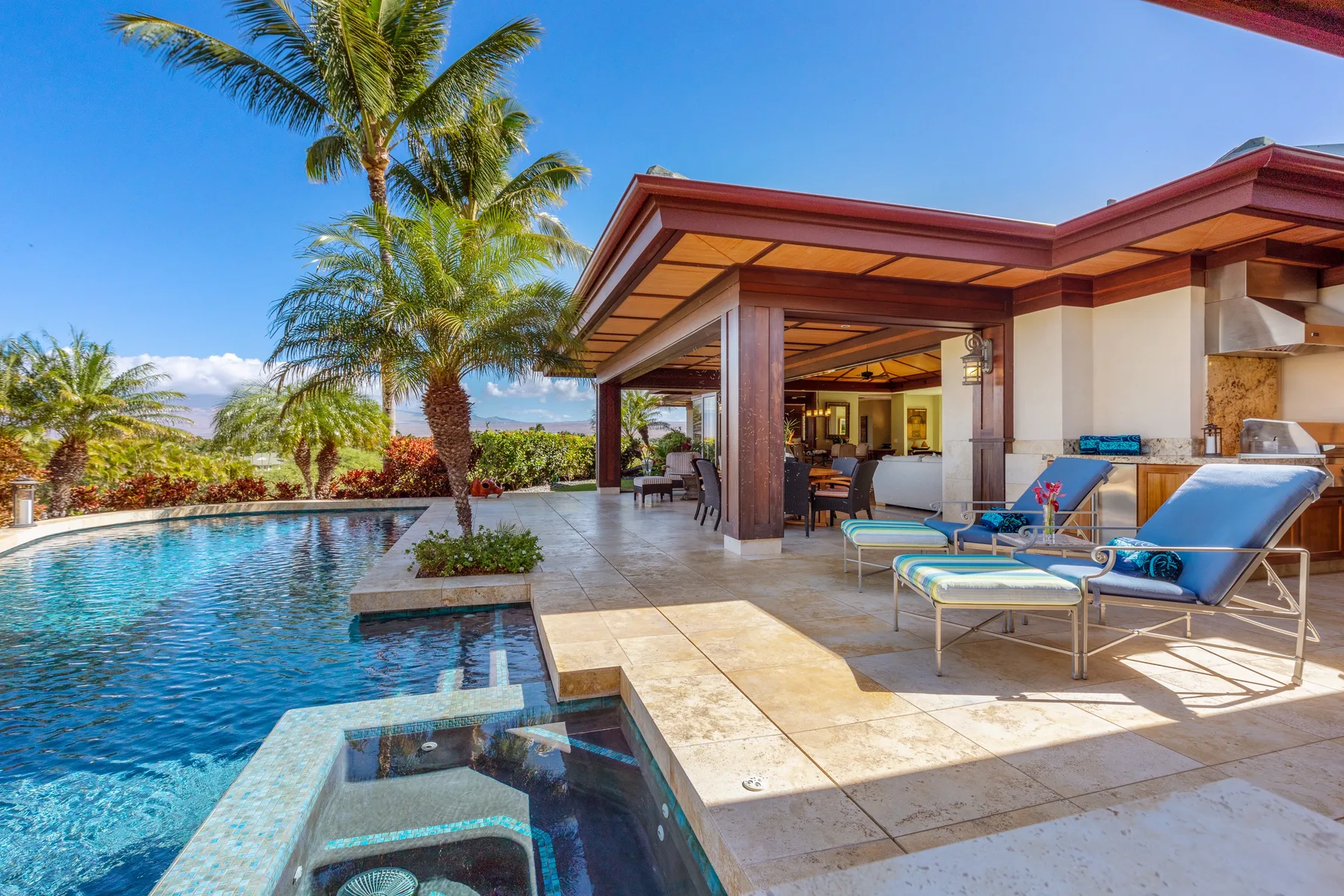 A poolside patio with lounge seating beside a covered outdoor living area.