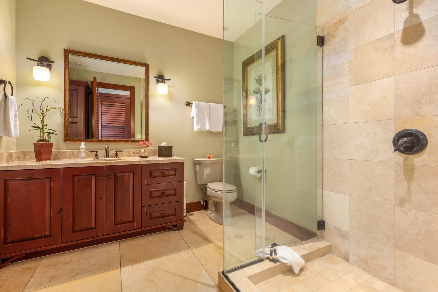 A bathroom with a long wooden vanity and a glass shower.