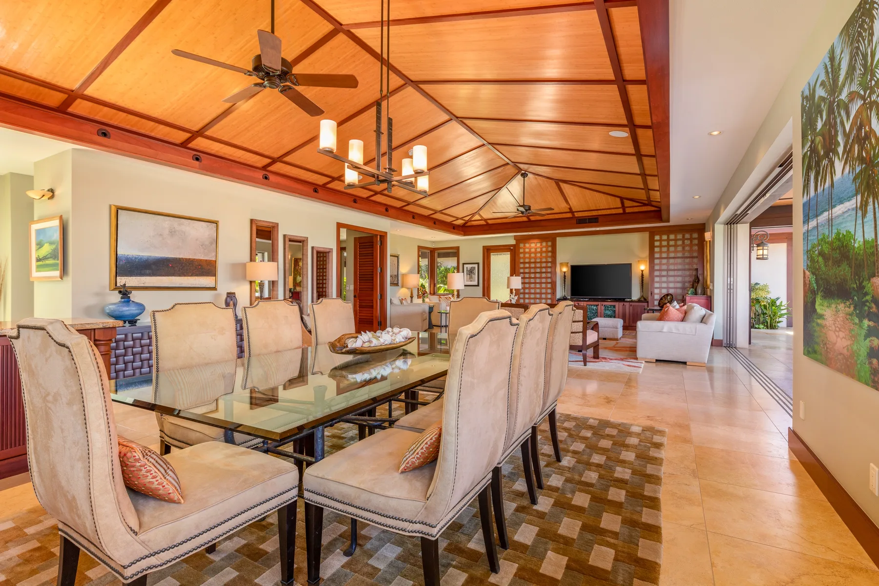 A spacious living and dining area with a long table and seating beneath a wood-paneled ceiling.