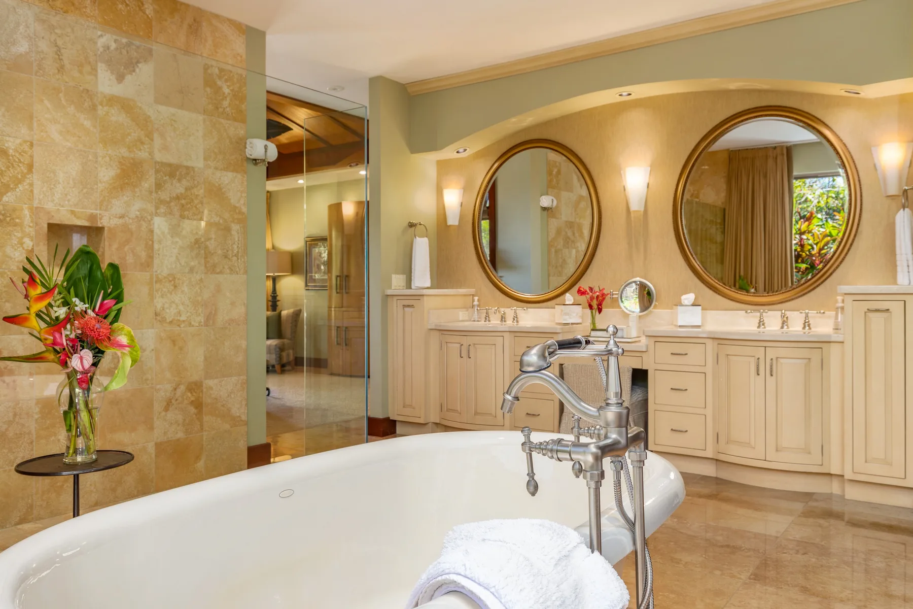 A bathroom with a bathtub, double vanity, and round mirrors.