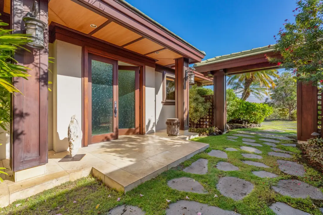 A house patio opens onto a garden path with stepping stones and greenery.