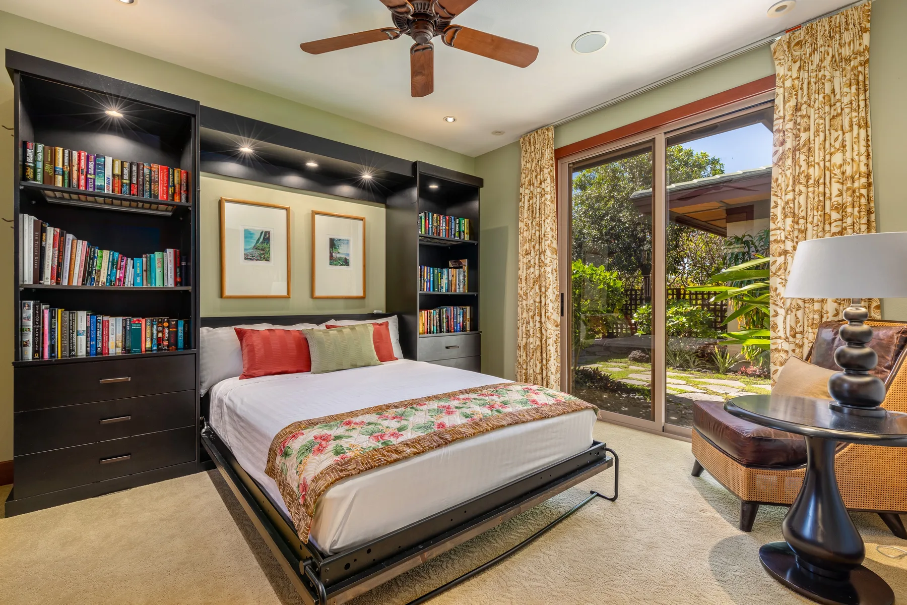 A bedroom with a bed, built-in bookshelves, and glass doors opening to a garden.