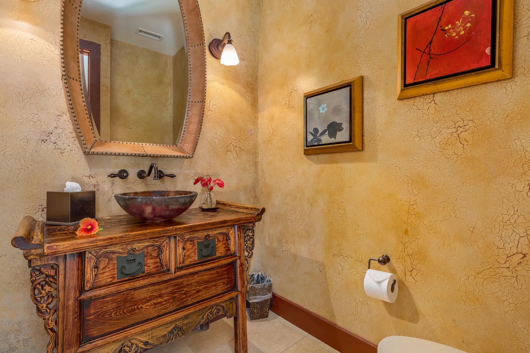 A rustic bathroom vanity with a basin sits beneath a large mirror.