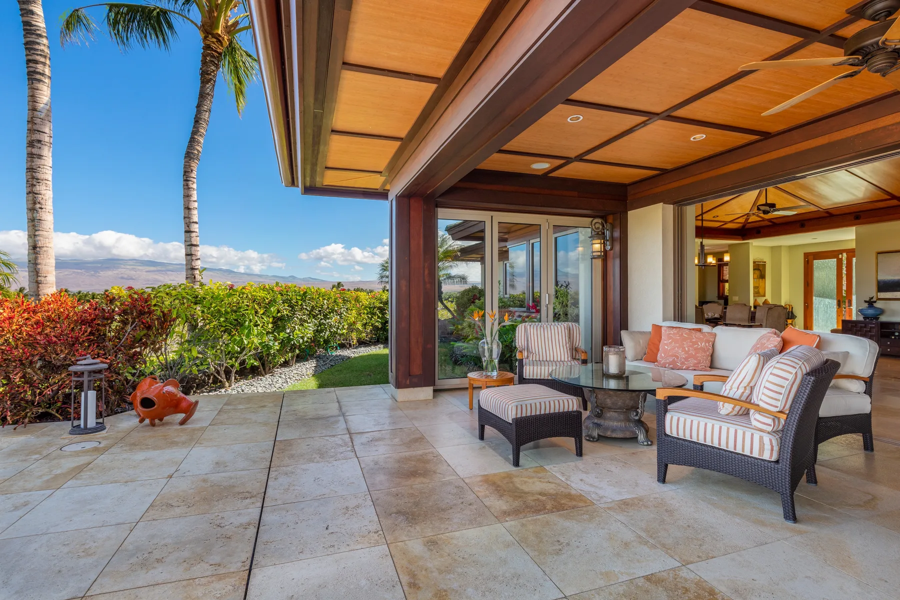 A covered outdoor patio with cushioned seating opens onto a garden.
