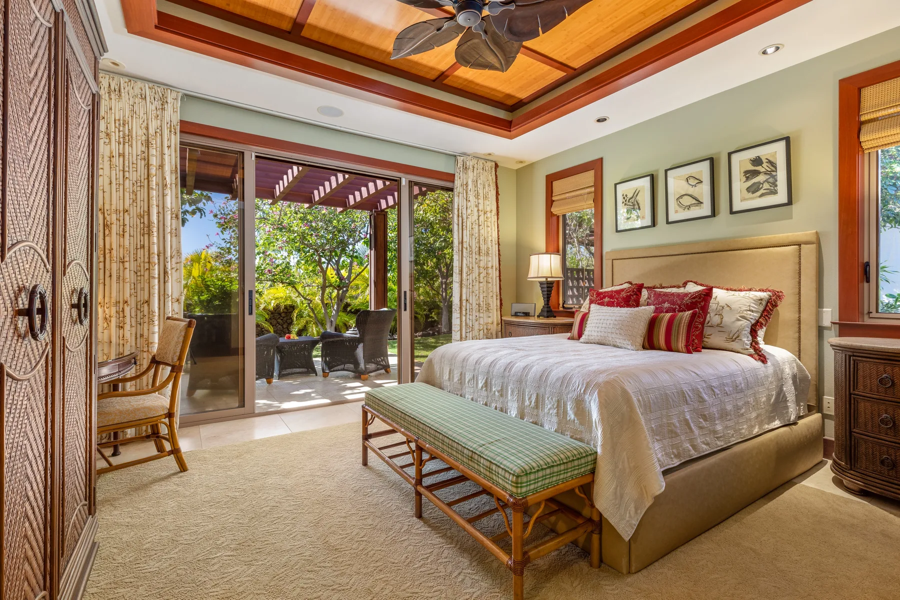 A bedroom with a bed, a bench, and sliding glass doors opening onto a patio.