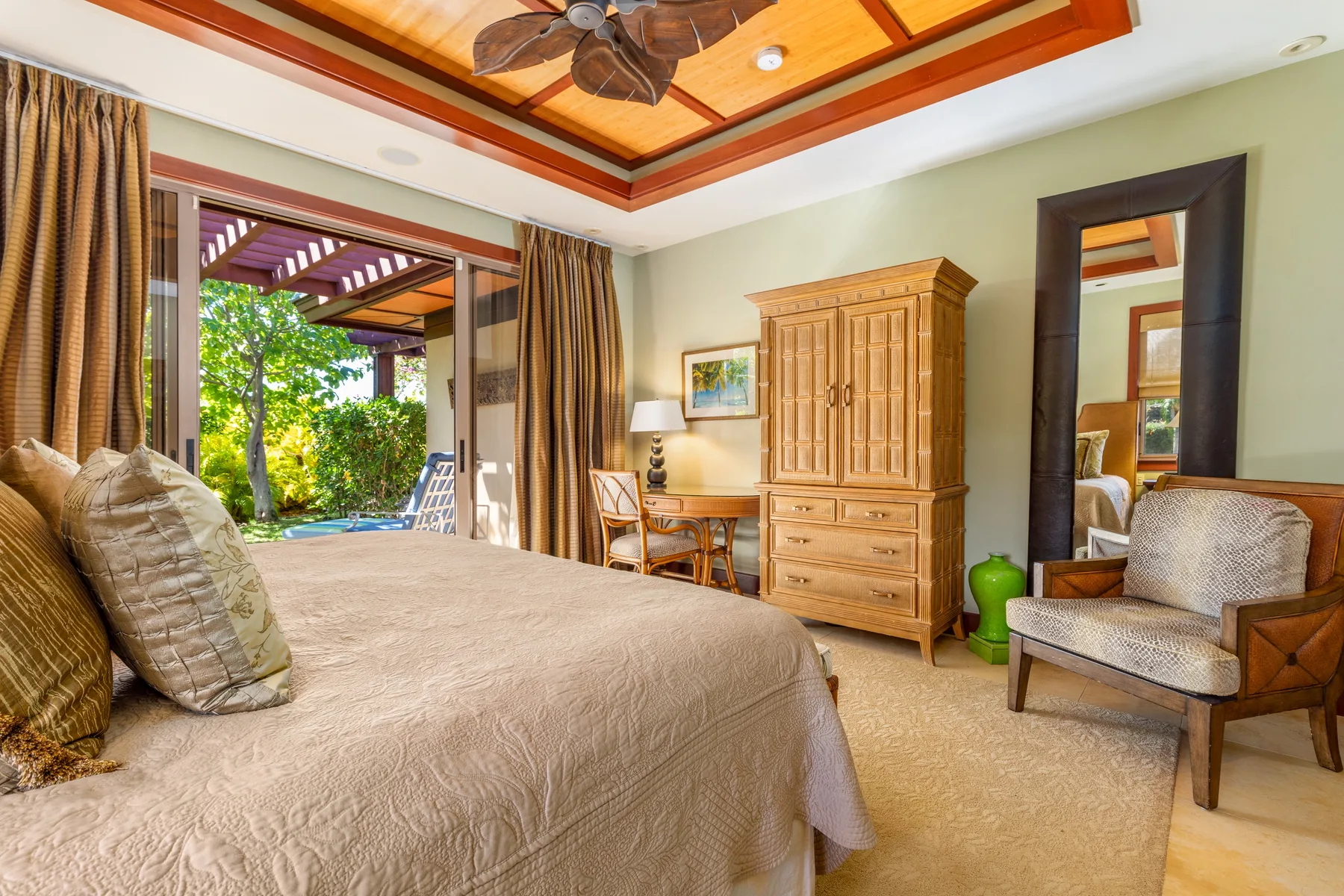 A bedroom with a large bed, wooden wardrobe, and an open doorway to greenery.